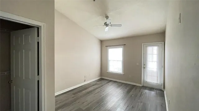 a view of empty room with wooden floor and fan