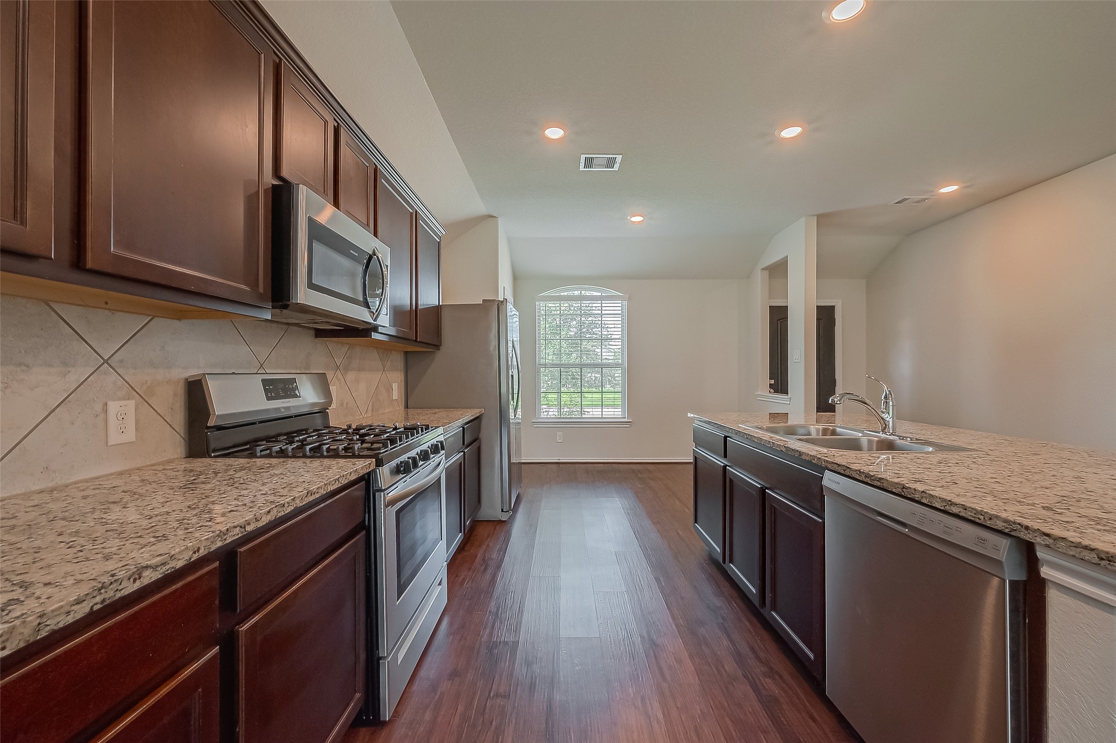 25911 Rustical Road Katy, TX 77493 - Photo 15 of 40 a kitchen with stainless steel appliances granite countertop wooden cabinets a stove top oven a sink and dishwasher