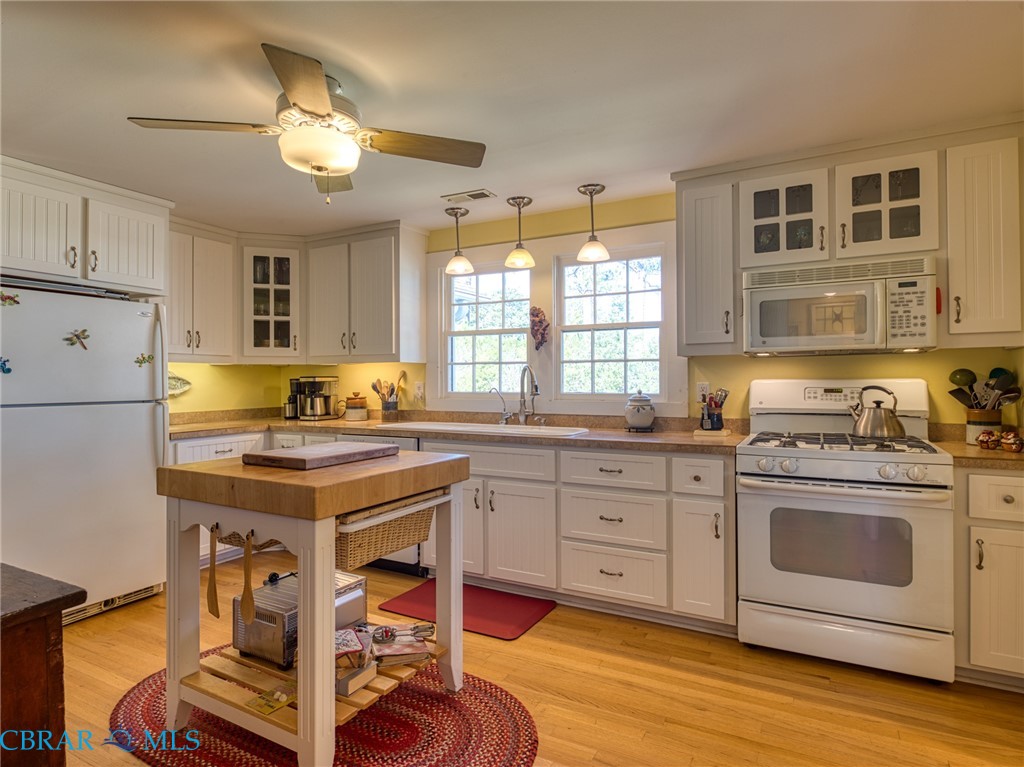 9078 Stump Point Road Hayes, VA 23072 - Photo 10 of 28 Kitchen with glass insert cabinets, white appliances, hanging light fixtures, and light wood finished floors