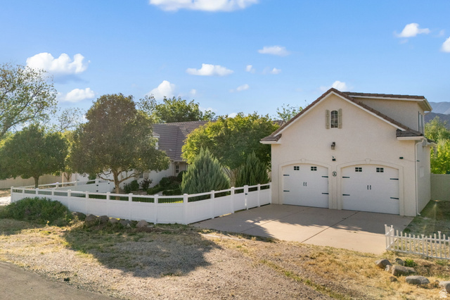 20 Valley Road Leeds, UT 84746 - Photo 52 of 57 Two-story detached garage featuring two carriage-style garage doors with windows, an upper-level window with shutters, and an exterior light fixture
