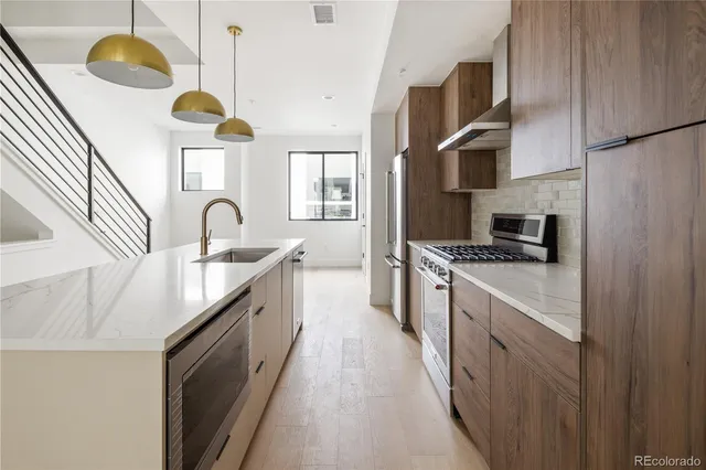 a kitchen with stainless steel appliances granite countertop a sink a stove and a refrigerator