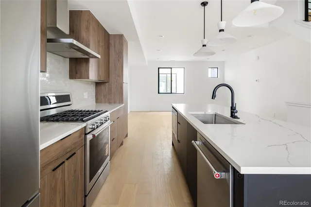 a kitchen with stainless steel appliances a sink a stove and a wooden floors