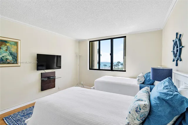 a bedroom with a bed and flat tv screen on the dresser