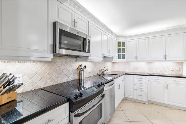 a kitchen with granite countertop white cabinets stainless steel appliances and a sink