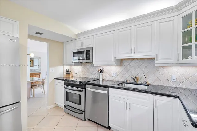 a kitchen with white cabinets and stainless steel appliances