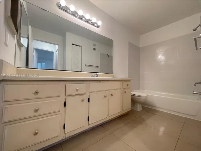 a spacious bathroom with a granite countertop toilet a double vanity sink a mirror and a bathtub