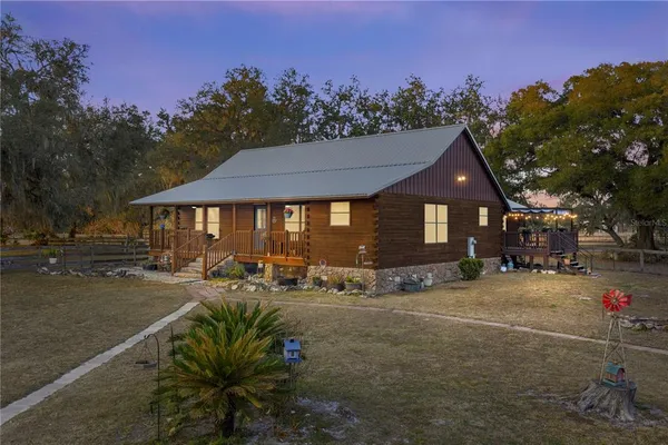 a front view of house with yard outdoor seating and covered with trees