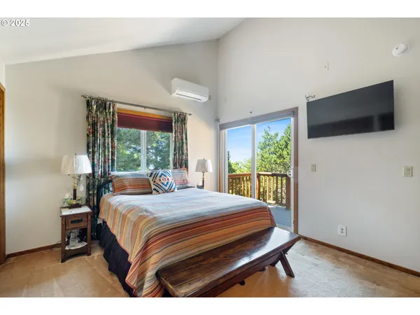 a bedroom with a large bed and a flat tv screen on dresser