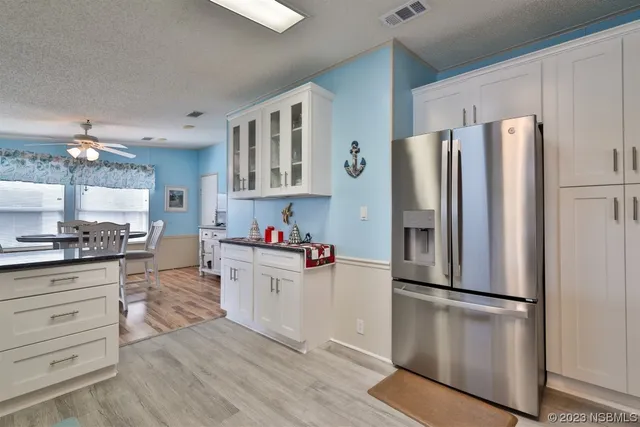 a kitchen with a refrigerator and white cabinets