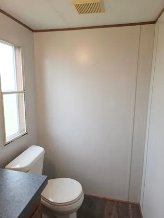 a white toilet sitting next to a window and a shower