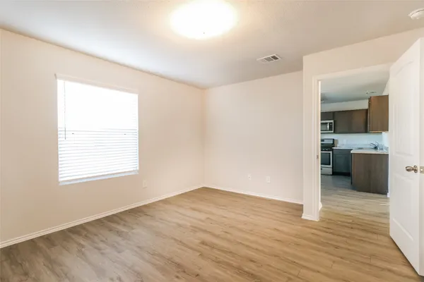 a view of a kitchen and an empty room with wooden floor and a kitchen