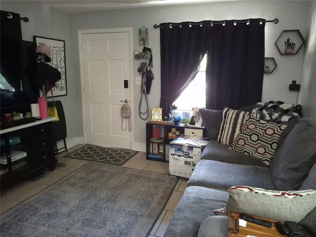 a living room with furniture a flat screen tv and a window