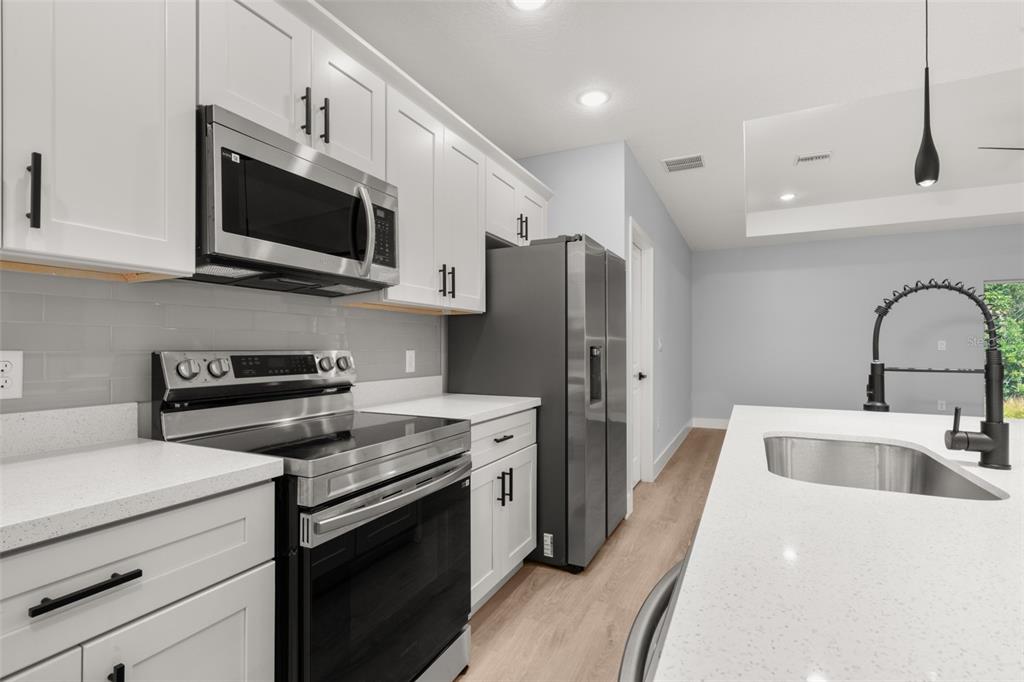 8736 Capilla Street Sebring, FL 33872 - Photo 16 of 60 a kitchen with stainless steel appliances a stove microwave and a sink