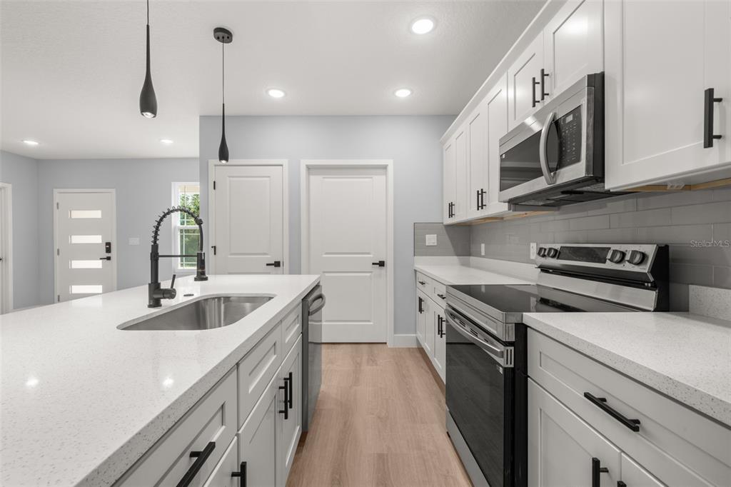 8736 Capilla Street Sebring, FL 33872 - Photo 18 of 60 a kitchen with stainless steel appliances granite countertop a sink a stove and a wooden floors