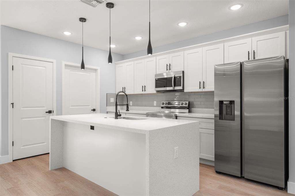 8736 Capilla Street Sebring, FL 33872 - Photo 20 of 60 a kitchen with kitchen island a sink stainless steel appliances and cabinets