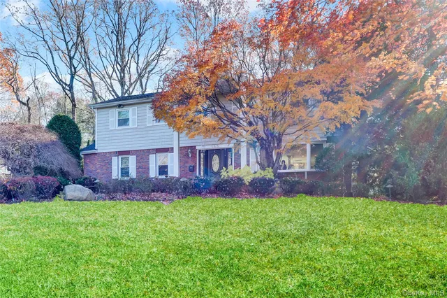 a view of a brick house with a big yard large trees and plants