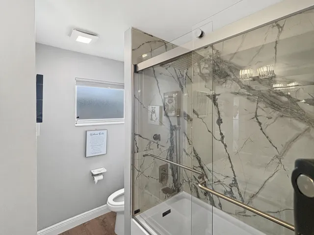 a bathroom with a granite countertop sink a toilet and shower