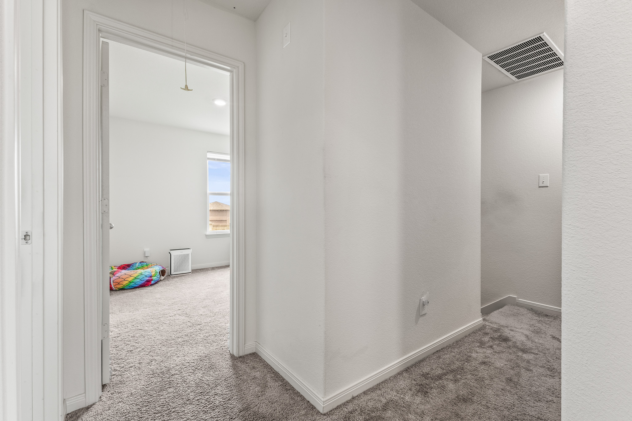 304 Hyacinth Way, Unit #7K Jarrell, TX 76537 - Photo 24 of 26 A well-lit hallway with plush carpeting and crisp white walls leads to a bright, inviting room.