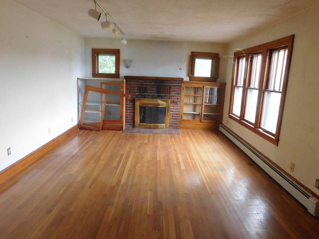 641 Northampton Street Holyoke, MA 01040 - Photo 9 of 19 an empty room with wooden floor fireplace and windows