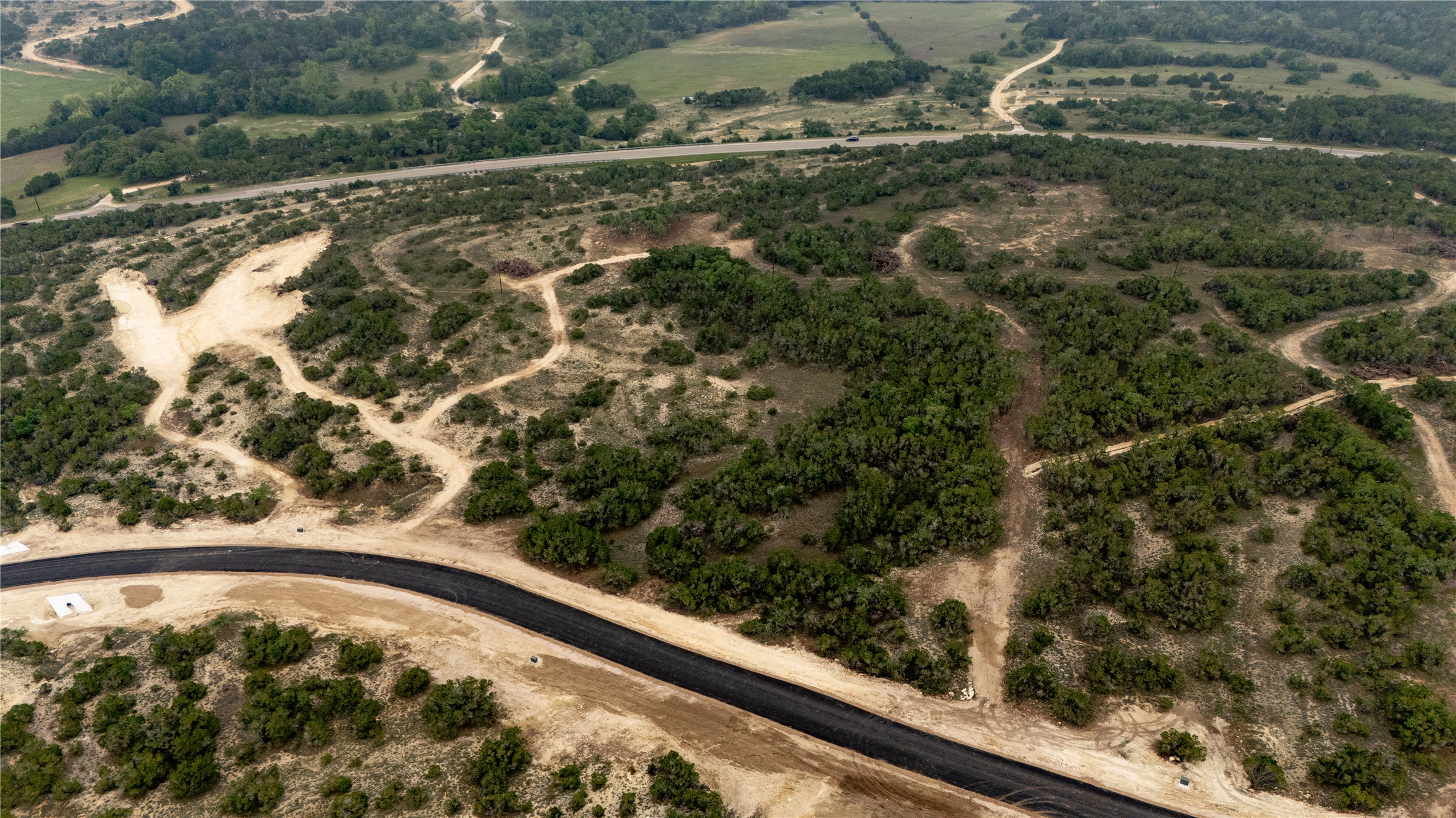 Lot 5 Ranch Road 165 Dripping Springs, TX 78620 - Photo 4 of 12 Expansive undeveloped land with abundant natural foliage and a newly paved road
