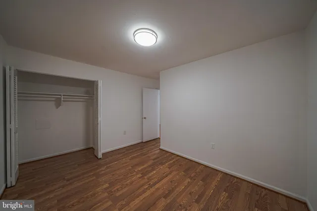 a view of an empty room with wooden floor and closet
