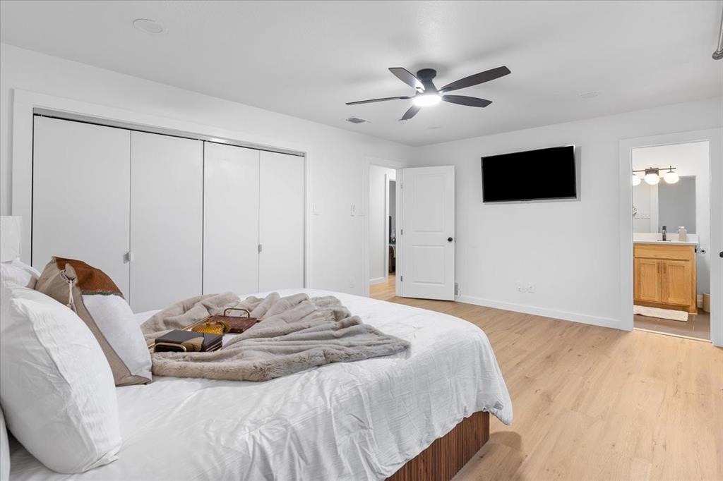 3509 West Sublett Road Arlington, TX 76017 - Photo 23 of 39 Wood-finish flooring, ceiling fan with integrated lighting, built-in closet with sliding doors, and a full bathroom featuring a wood-finish vanity