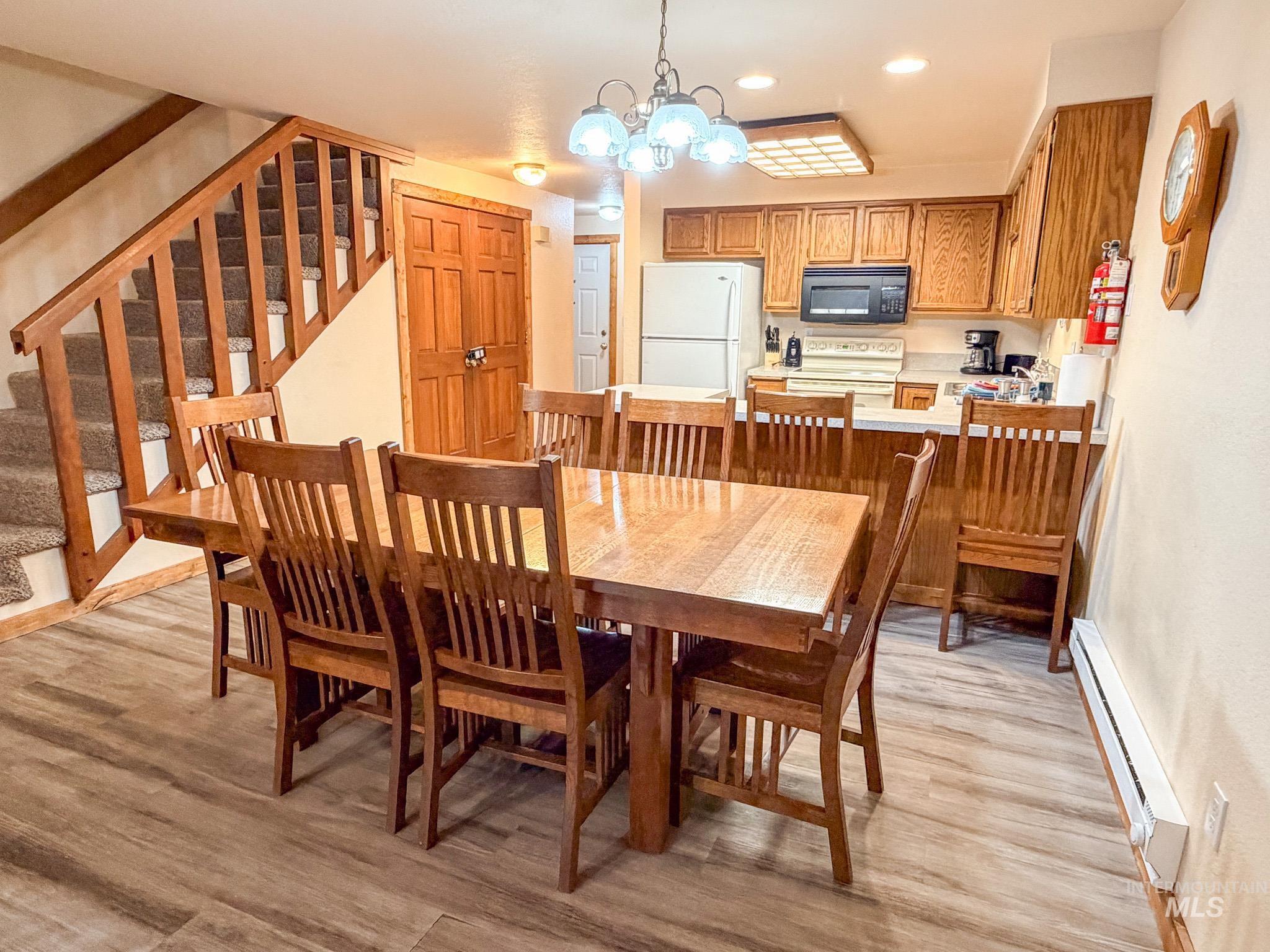 1630 Davis Avenue, Unit F46 McCall, ID 83638 - Photo 11 of 23 Dining space featuring a chandelier, stairs, recessed lighting, a baseboard heating unit, and light wood-style floors