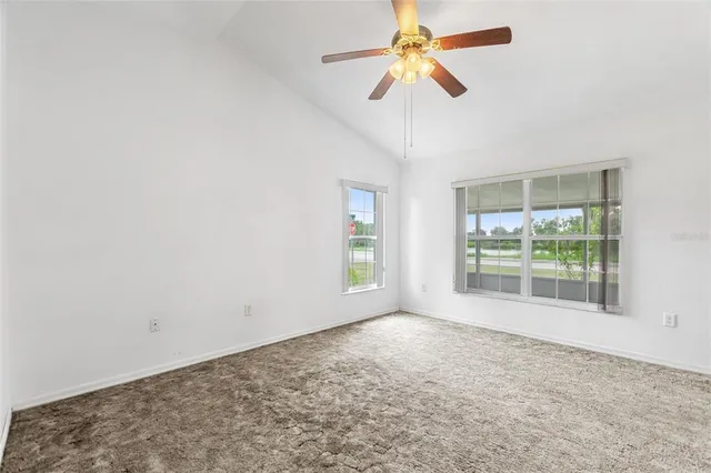 en empty room with windows and ceiling fan