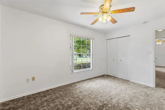 an empty room with windows and chandelier fan