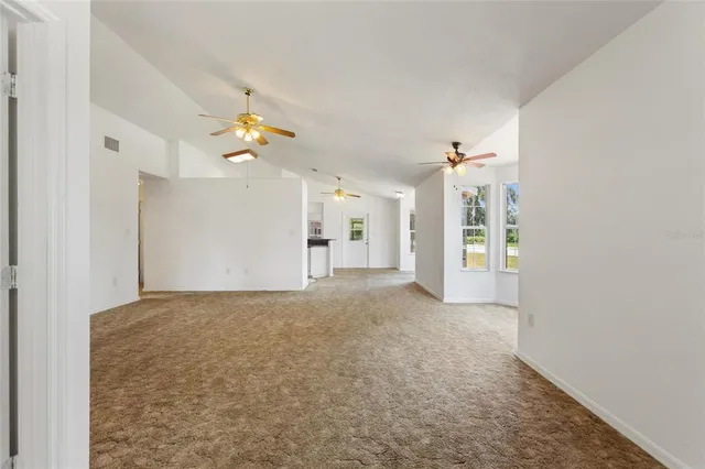 a view of a big room with a chandelier fan and windows