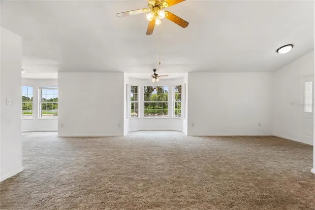 an empty room with windows and ceiling fan