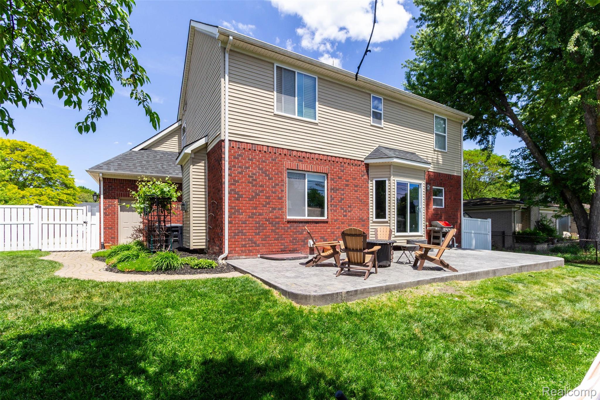 36039 Curtis Road Livonia, MI 48152 - Photo 53 of 61 Rear exterior featuring a brick and siding facade, a ground-level patio, a fenced perimeter, and mature trees