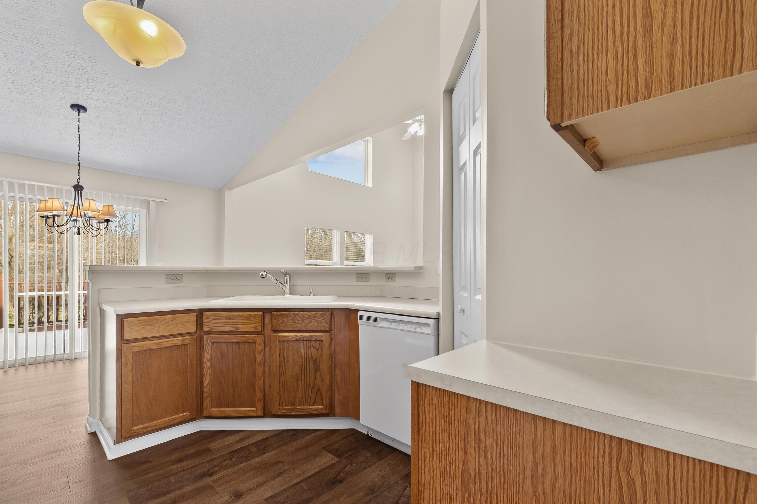 30 Tabilore Loop Delaware, OH 43015 - Photo 20 of 55 • New luxury vinyl plank flooring ~ 2025 • Tan painted walls • Oak framed cabinets • Double bowl sink with sprayer • Vaulted ceiling • Frigidaire® refrigerator • Frigidaire® electric range • Frigidaire® dishwasher • General Electric® microwave • Breakfast bar ledge • Chandelier • Step-in pantry closet