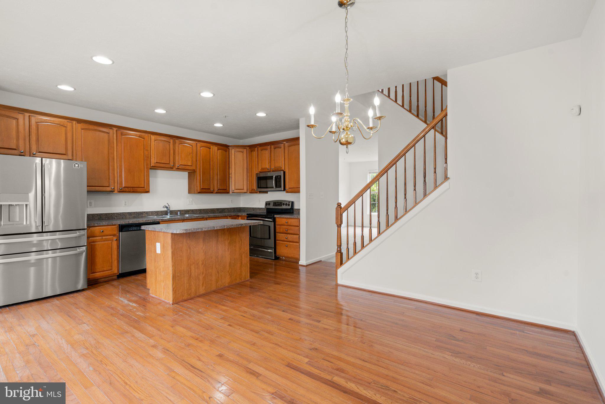 887 Middle River Road Middle River, MD 21220 - Photo 17 of 42 a kitchen with stainless steel appliances granite countertop a refrigerator a sink dishwasher a s stove top oven a dining table and chairs with wooden floor
