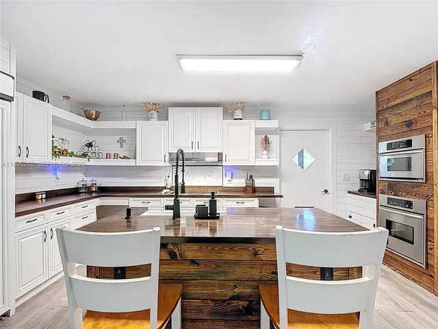 a kitchen with kitchen island a stove a sink dishwasher and white cabinets with wooden floor