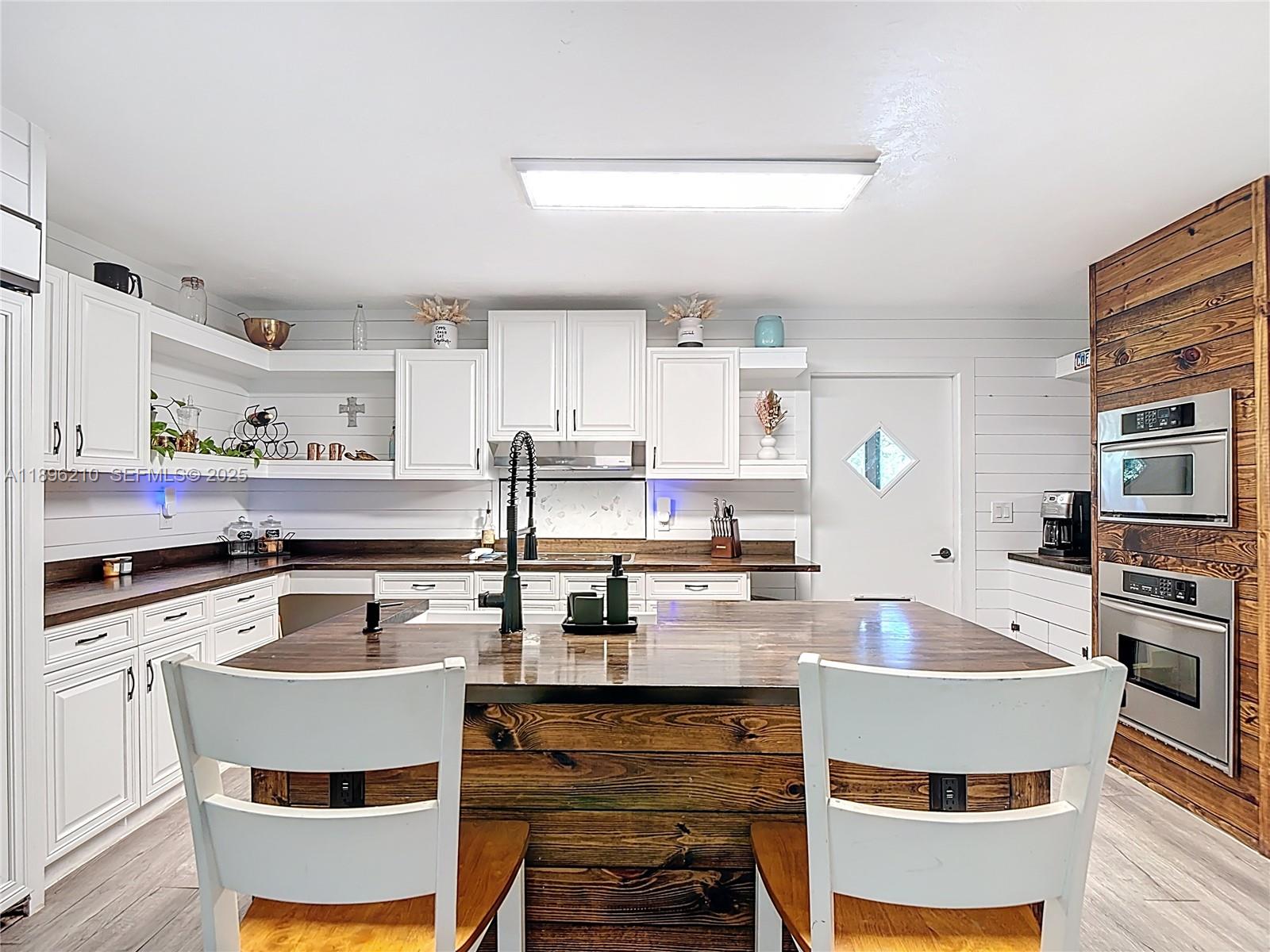 1270 Tom Coker Road LaBelle, FL 33935 - Photo 12 of 46 a kitchen with kitchen island a stove a sink dishwasher and white cabinets with wooden floor