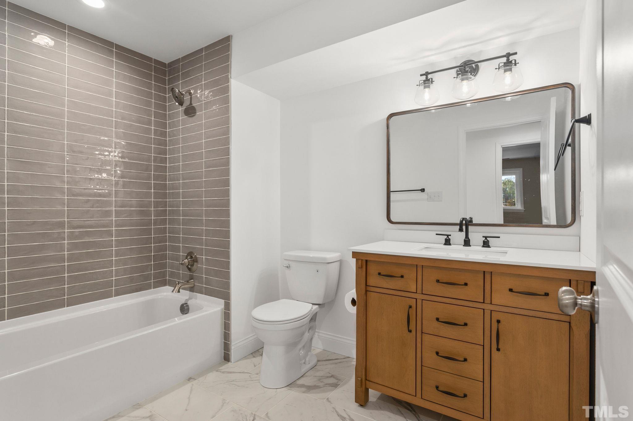 311 Lord Ashley Road Raleigh, NC 27610 - Photo 27 of 39 a bathroom with a granite countertop sink a toilet mirror and bathtub