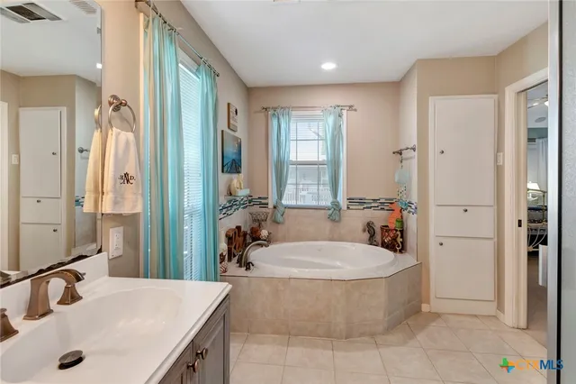 a bathroom with a tub a sink a mirror and shower