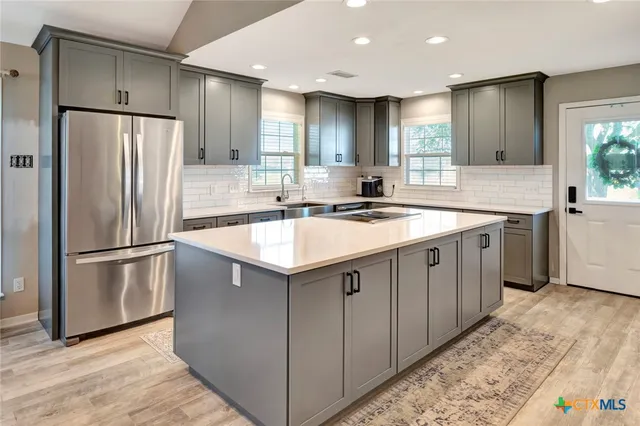 a kitchen with a sink a refrigerator a microwave and island with wooden floor