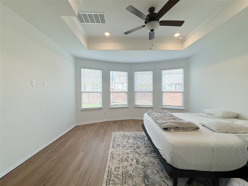 253 Inlet Lane Leander, TX 78641 - Photo 11 of 23 Bedroom featuring wood finished floors, ornamental molding, a raised ceiling, a ceiling fan, and recessed lighting