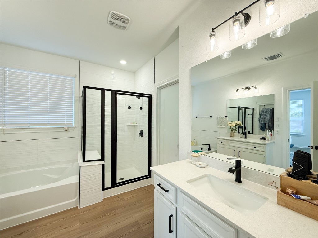 253 Inlet Lane Leander, TX 78641 - Photo 12 of 23 Full bathroom with vanity, a bath, a shower stall, and light wood-style floors