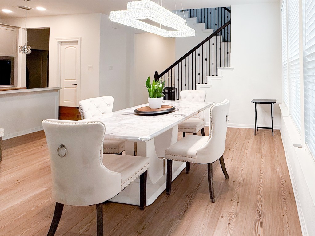 253 Inlet Lane Leander, TX 78641 - Photo 6 of 23 Dining space with light wood finished floors, a chandelier, and stairs