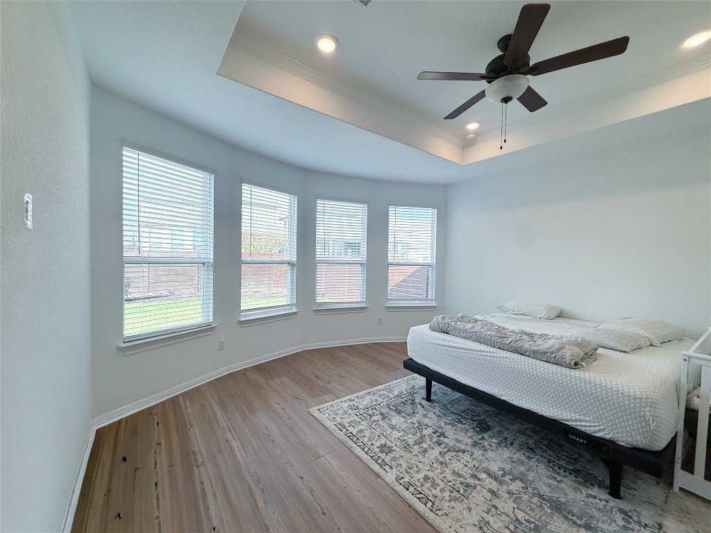 253 Inlet Lane Leander, TX 78641 - Photo 10 of 23 Bedroom featuring ceiling fan, wood-type flooring, a tray ceiling, crown molding, and recessed lighting
