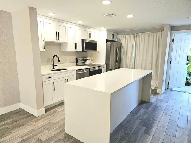 a kitchen with stainless steel appliances a refrigerator sink and microwave