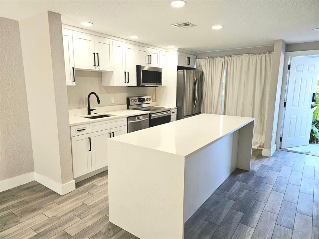 1102 Jeffery Street Boca Raton, FL 33487 - Photo 5 of 14 a kitchen with stainless steel appliances a refrigerator sink and microwave