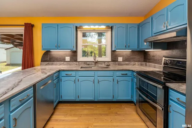 a kitchen with granite countertop stainless steel appliances wooden cabinets a stove a sink and a window