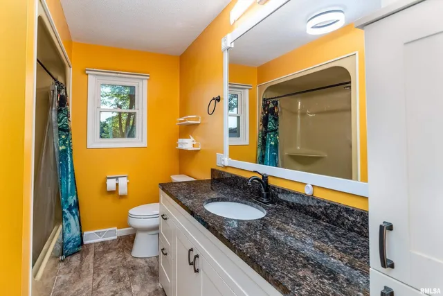 a bathroom with a granite countertop sink and a mirror