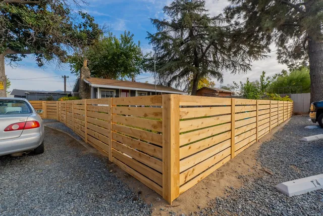 a backyard of house with potted plants and large tree