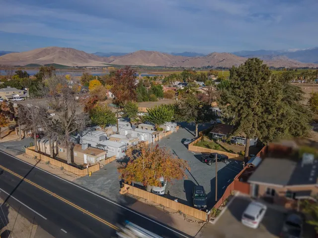 an aerial view of a residential houses with outdoor space and trees