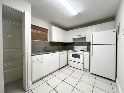 a white kitchen with cabinets a sink and white appliances